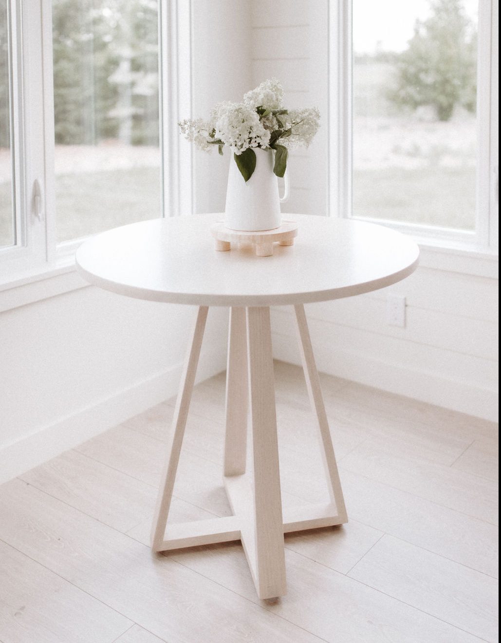 White stained bistro table in bright sunroom.